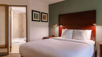 Een hotelkamer met een groot bed, een houten hoofdbord, een nachtkastje, een wandlamp en een lijst met een afbeelding.