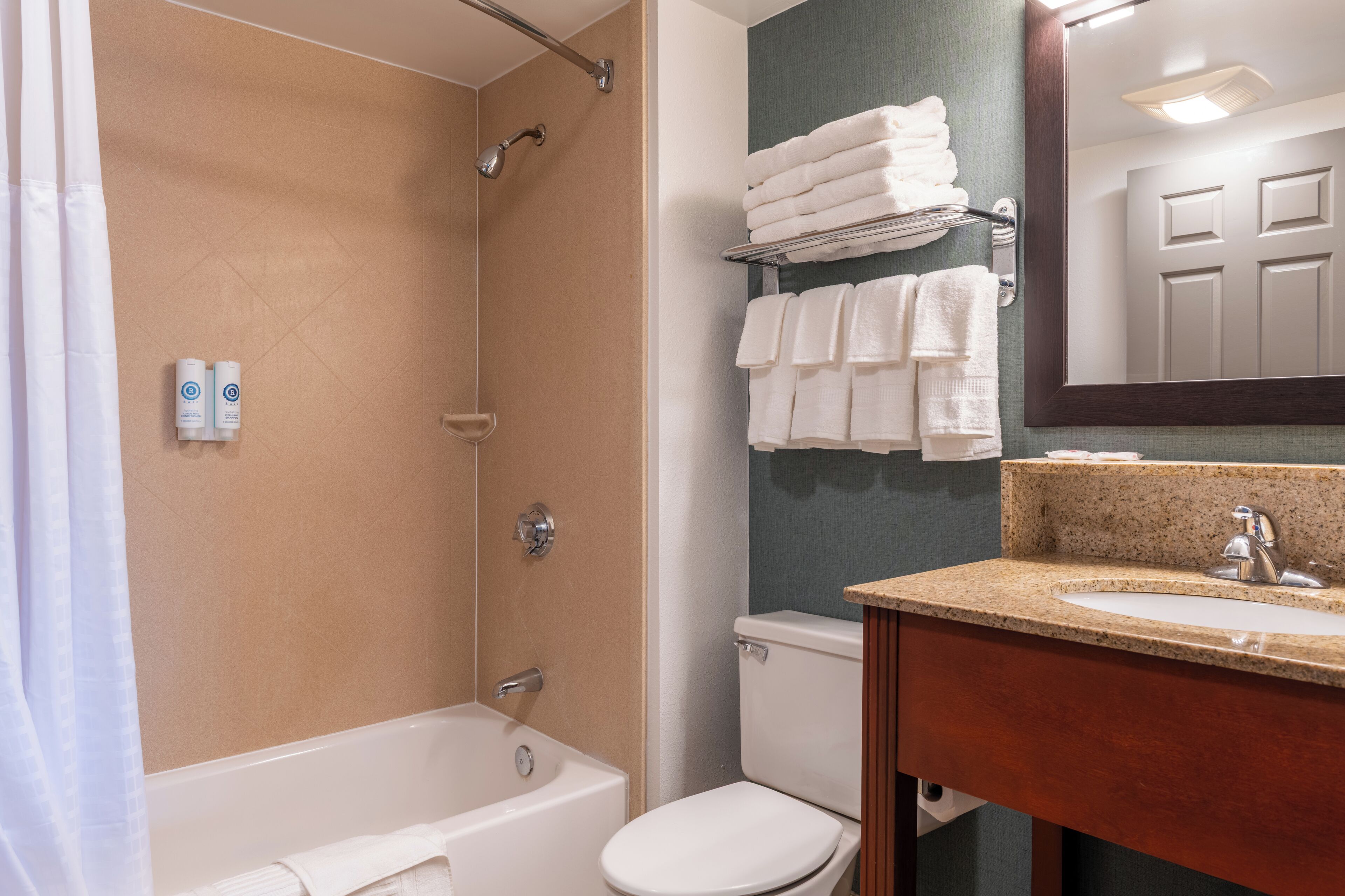A bathroom with a bathtub, toilet, and sink. There are towels on a rack and a mirror above the sink.