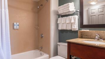 A bathroom with a bathtub, toilet, and sink. There are towels on a rack and a mirror above the sink.