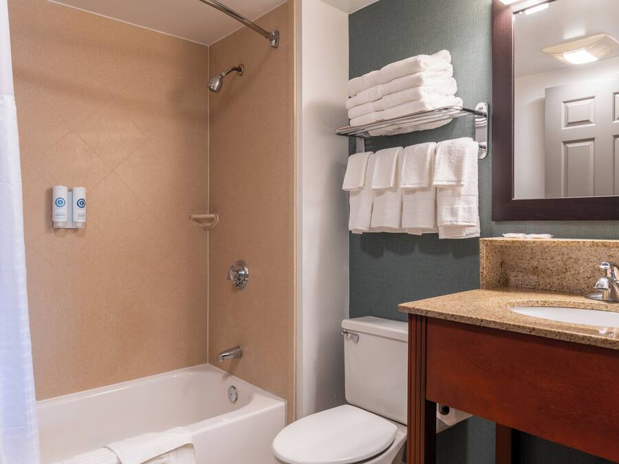 A bathroom with a bathtub, toilet, and sink. There are towels on a rack and a mirror above the sink.