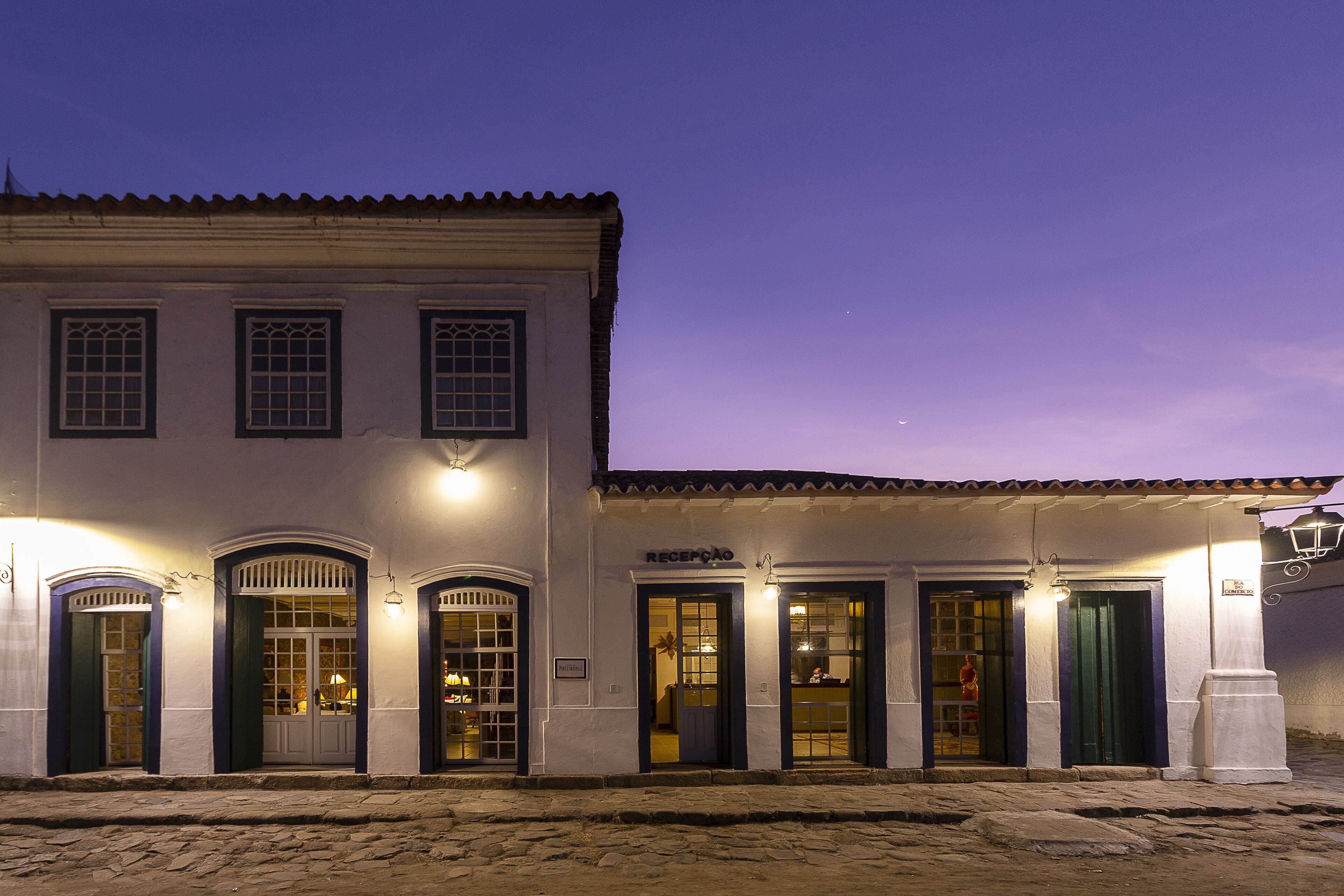 Un edificio con varias puertas y ventanas, algunas con paneles de vidrio, y un letrero sobre una puerta que dice "RECEPTION".