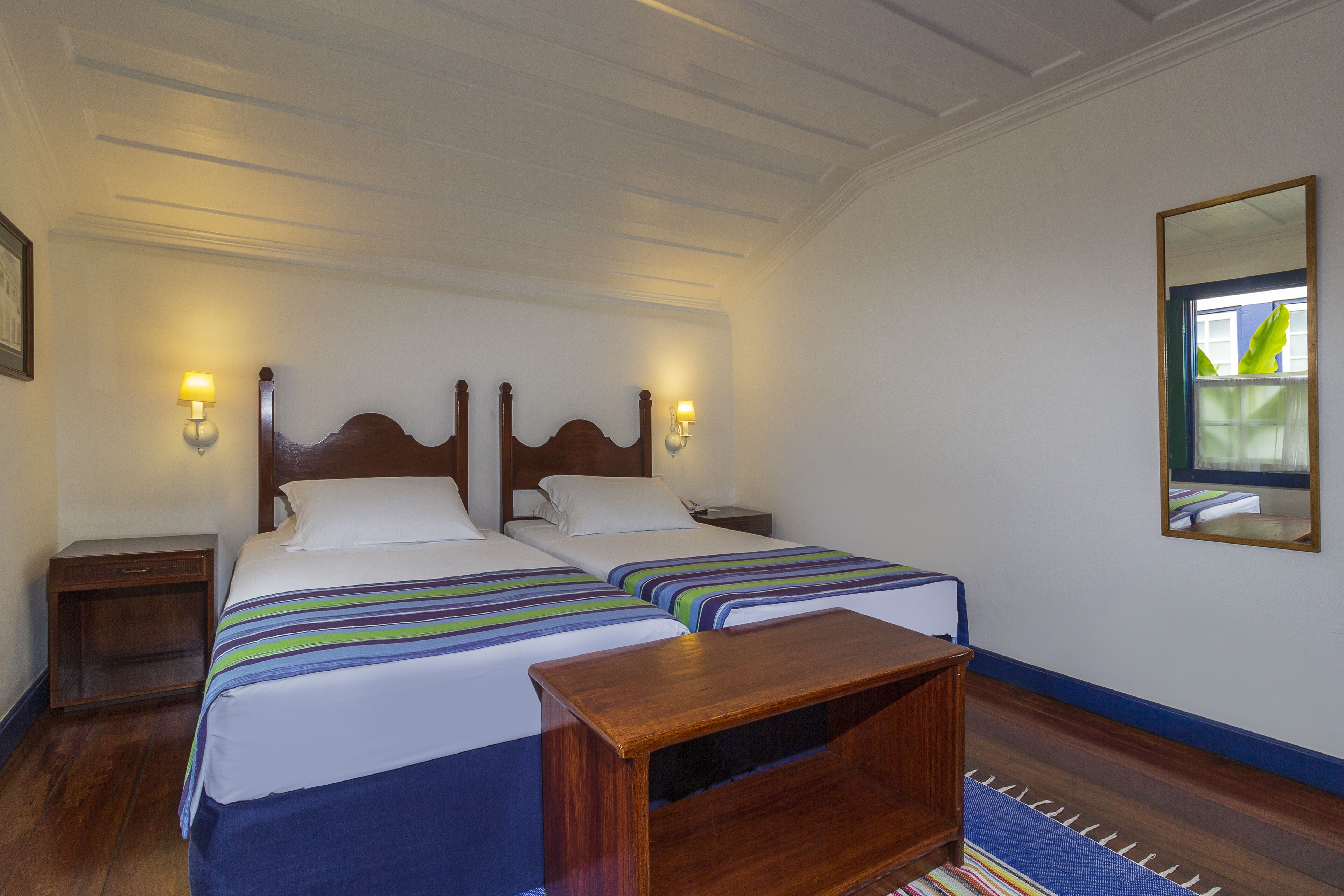 A double bed with a wooden headboard, two bedside tables with lamps, and a mirror on the wall.