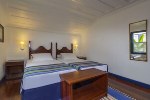 Una cama doble con cabecera de madera, dos mesitas de noche con lámparas y un espejo en la pared.