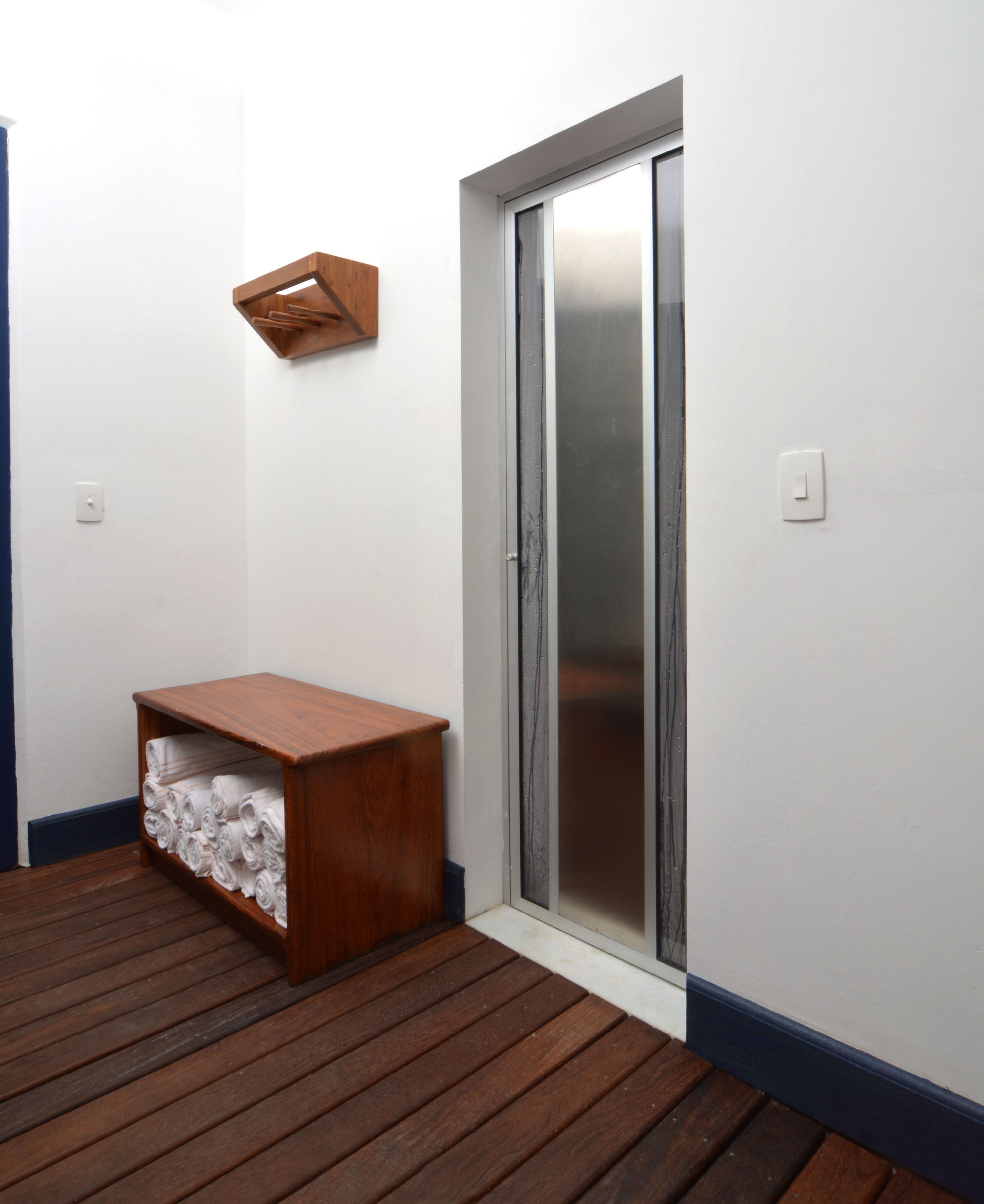 A room with a wooden bench, a towel rack, and a sliding glass door.
