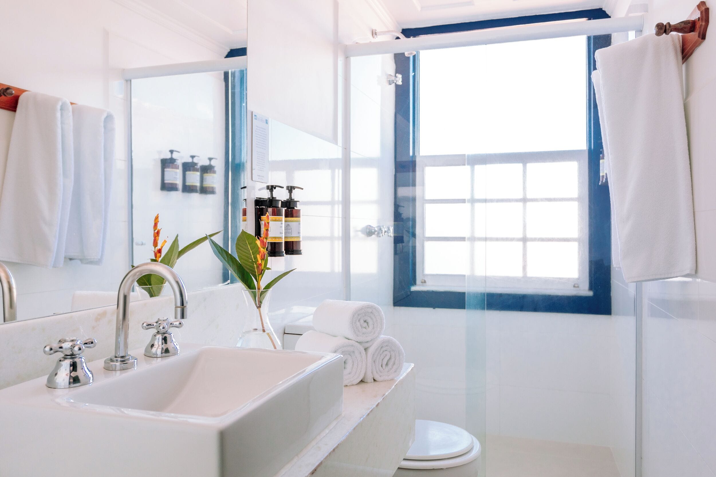 Un baño moderno con un lavamanos grande, dos grifos, un espejo y una ventana con vistas.