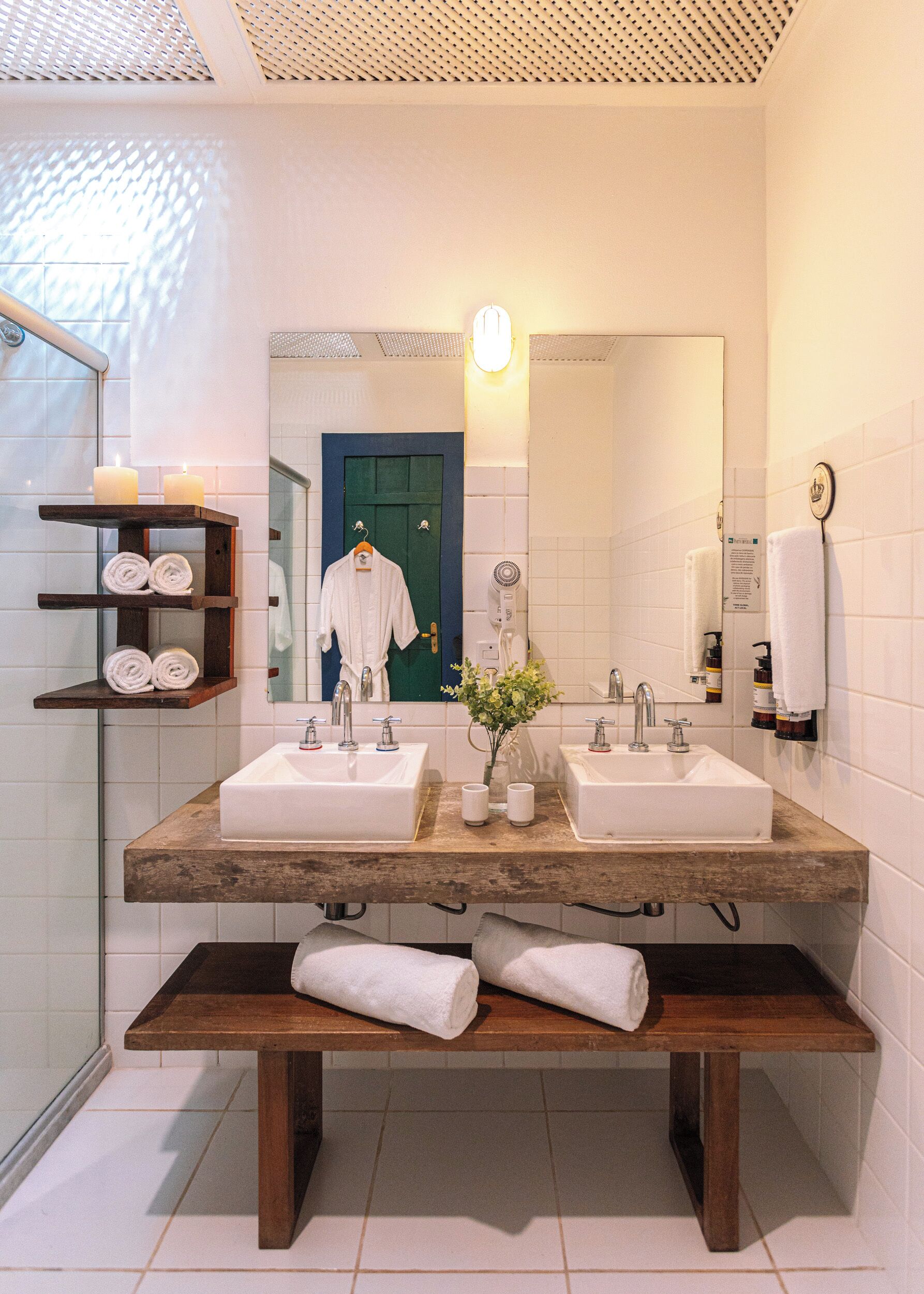 A bathroom with two sinks, a mirror, a towel rack, and a bench.