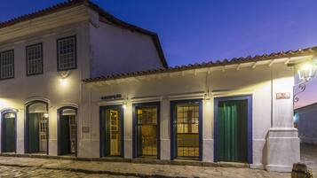 A building with multiple doors and windows, a cobblestone street, and a sign indicating a commercial area.