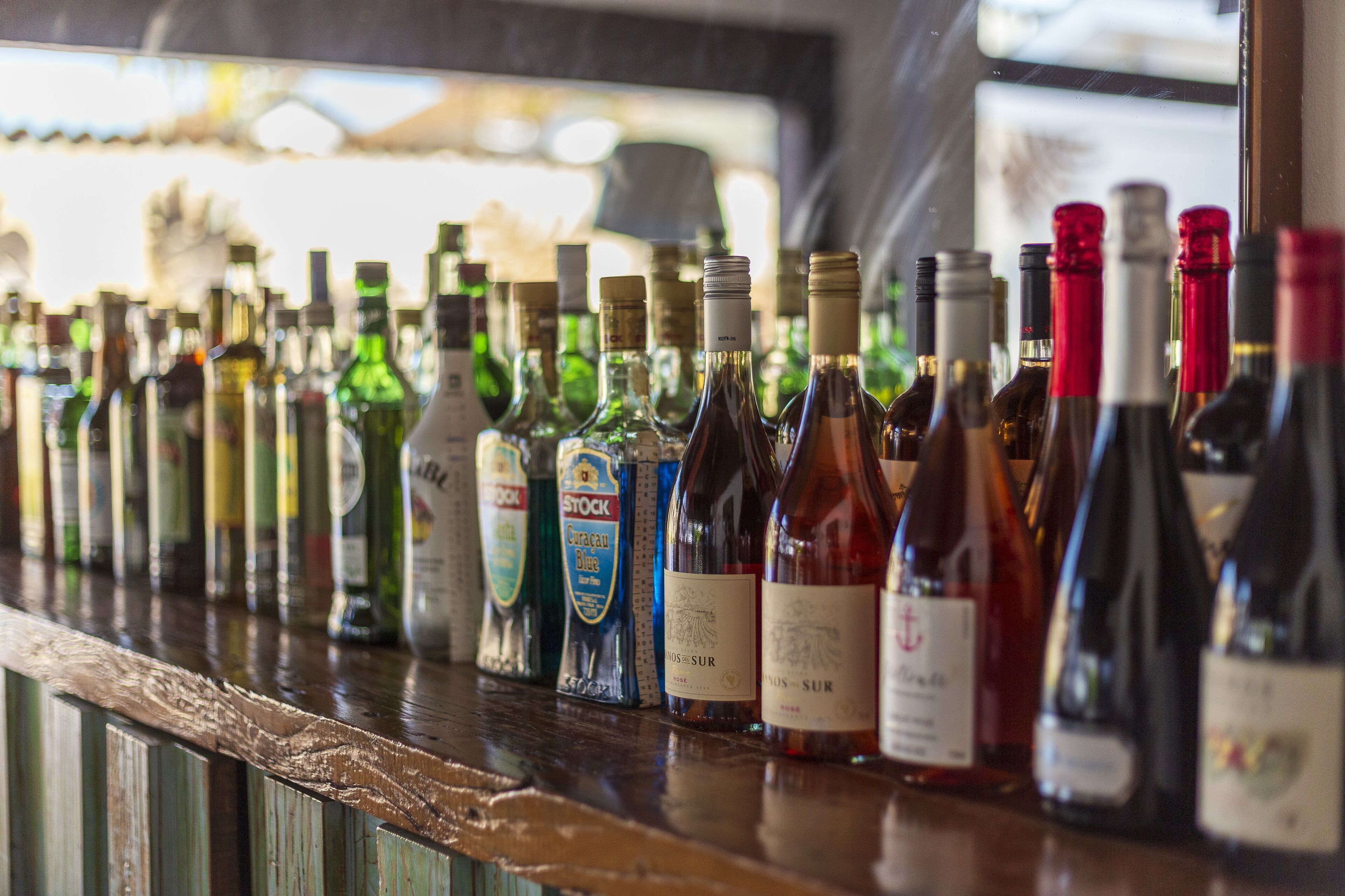 Un comptoir de bar où sont alignées différentes bouteilles d’alcool, notamment du vin et des spiritueux.