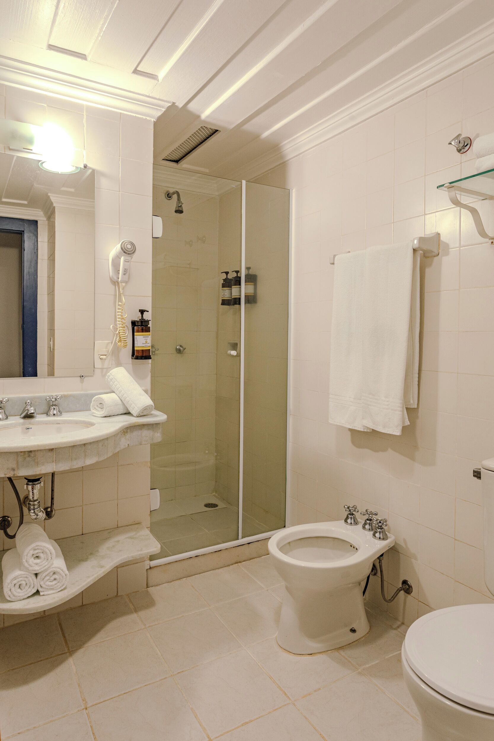 A bathroom with a glass-enclosed shower, a toilet, and a sink with a towel rack.