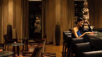 Ein schwach beleuchtetes Restaurant mit einer Frau, die an einem Tisch sitzt, umgeben von Stühlen und Tischen.