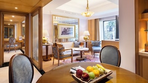 A well-lit hotel room with a dining area, a sofa, a coffee table, and a chandelier. - Trident, Bhubaneswar (Bhubaneshwar)