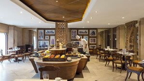 A restaurant with a central buffet, multiple dining tables, and chairs. - Trident, Bhubaneswar (Bhubaneshwar)