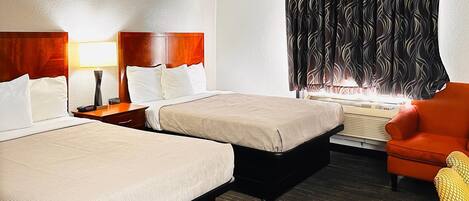 A hotel room with two beds, a heater, a chair, and a window with patterned curtains.