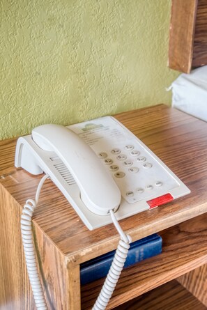A white telephone on a wooden desk with a coiled cord. - OYO Hotel Brownwood Hwy 67 (Brownwood)