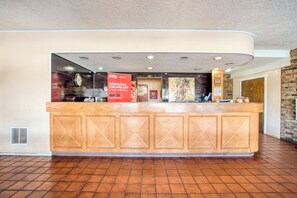 A reception desk with a wooden finish, a clock, and a sign promoting the OYO app.