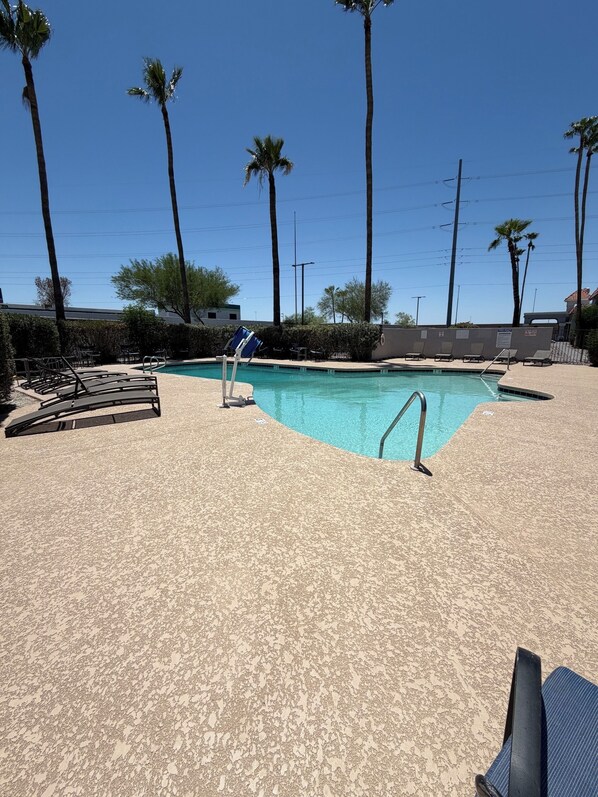 Una piscina con sillones de playa y palmeras.
