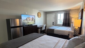 A hotel room with two beds, a desk, a television, and a refrigerator. - Extend-a-Suites Phoenix (Phoenix)