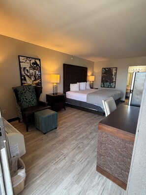 A hotel room with a bed, two bedside tables with lamps, a chair, a desk, and a trash bin. - Extend-a-Suites Phoenix (Phoenix)