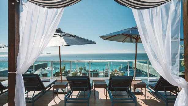 Una terraza con sillones de descanso y sombrillas con vista al mar.