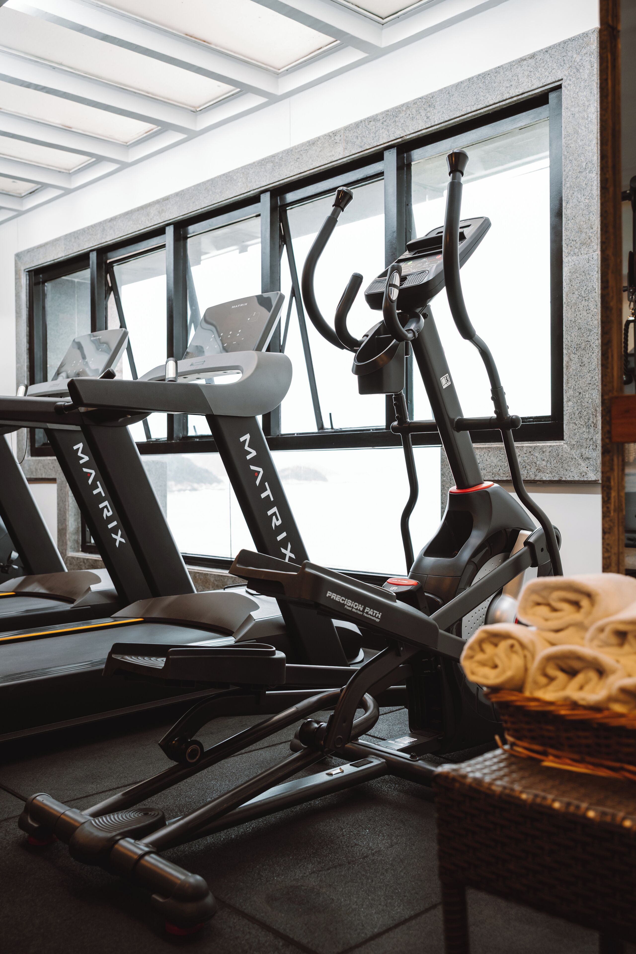 A gym with treadmills labeled 'Matrix' and a basket of towels on a table.