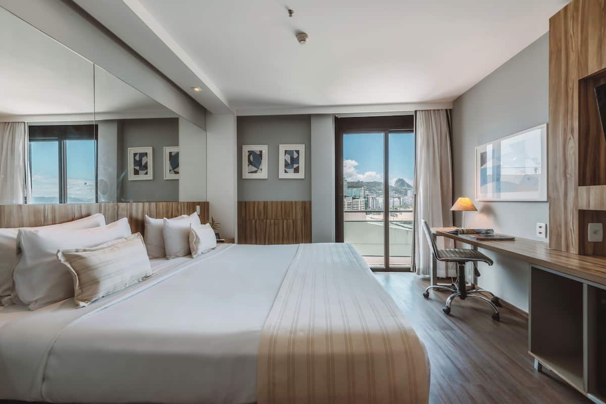 Une chambre d’hôtel avec un grand lit, un bureau et une vue sur la ville.
