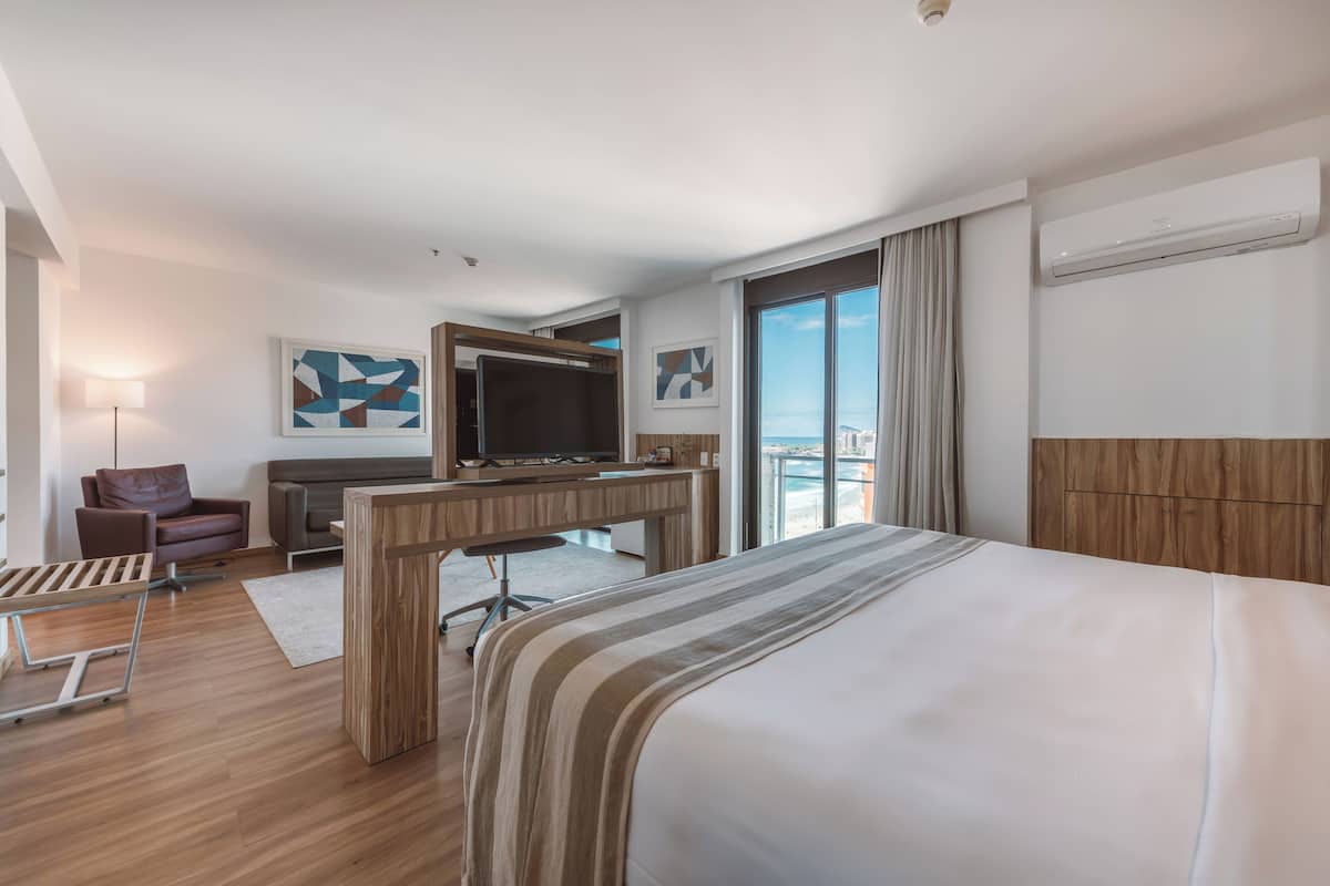 Une chambre d’hôtel avec un lit, un bureau, une télévision et une vue sur la ville.