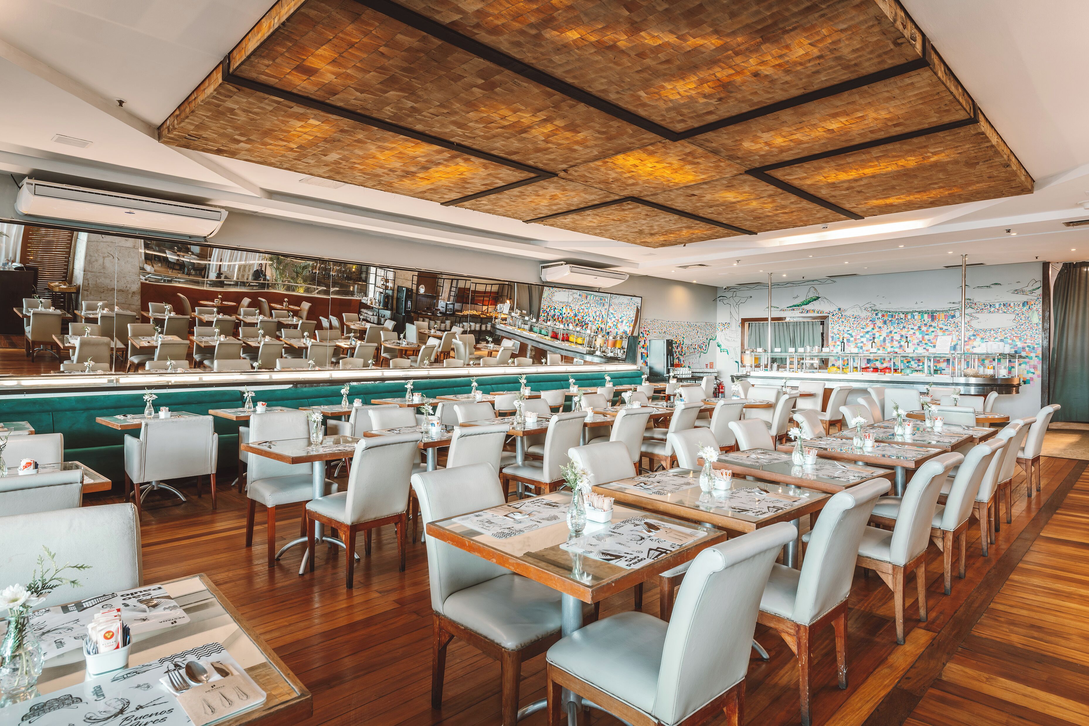 Een restaurant met een bar, houten vloeren en een hoge plafond met zichtbare balken.