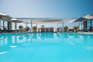 Una piscina al aire libre, sombrillas, sillones reclinables de piscina