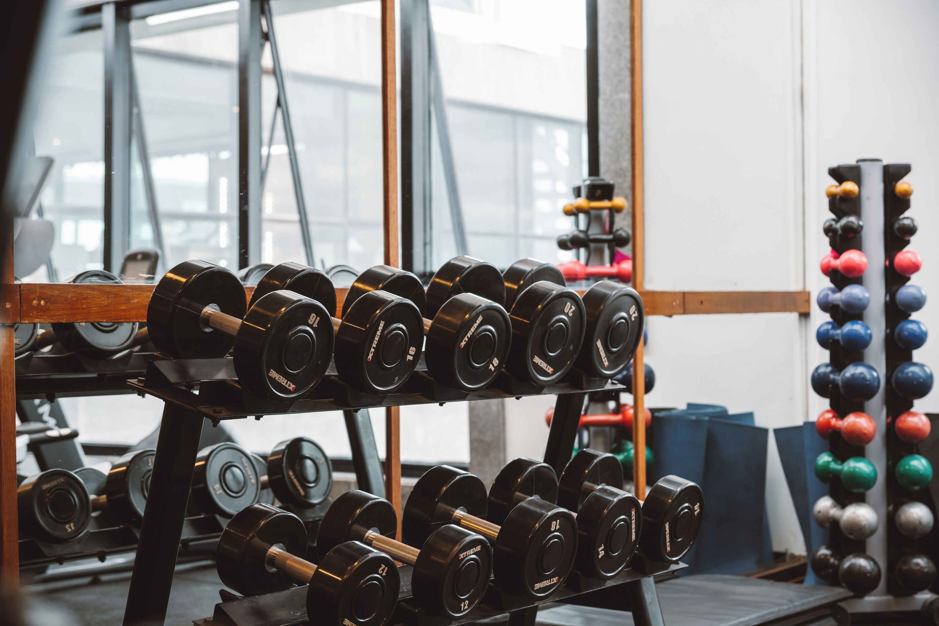 Een sportschool met krachttoestellen, waaronder dumbbells en een kettlebellrek.
