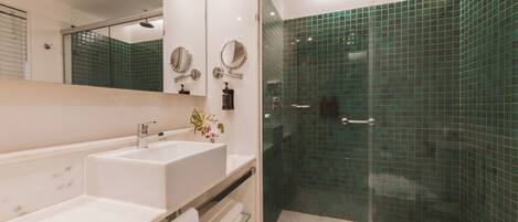 Une salle de bain moderne avec une douche à parois de verre, un lavabo blanc et un miroir.
