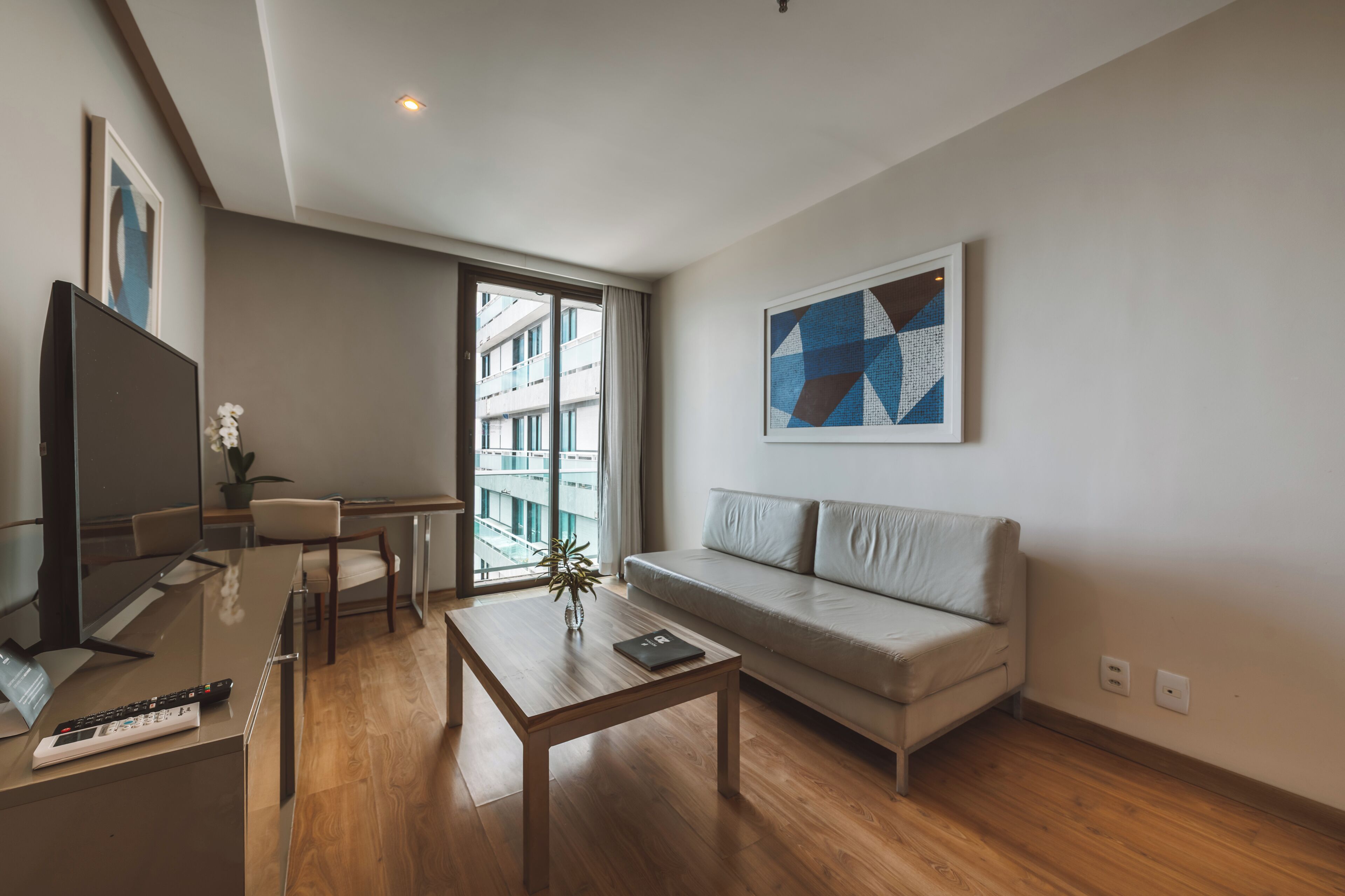 Una sala de estar moderna con un sofá, una mesa de centro, un televisor y un comedor.