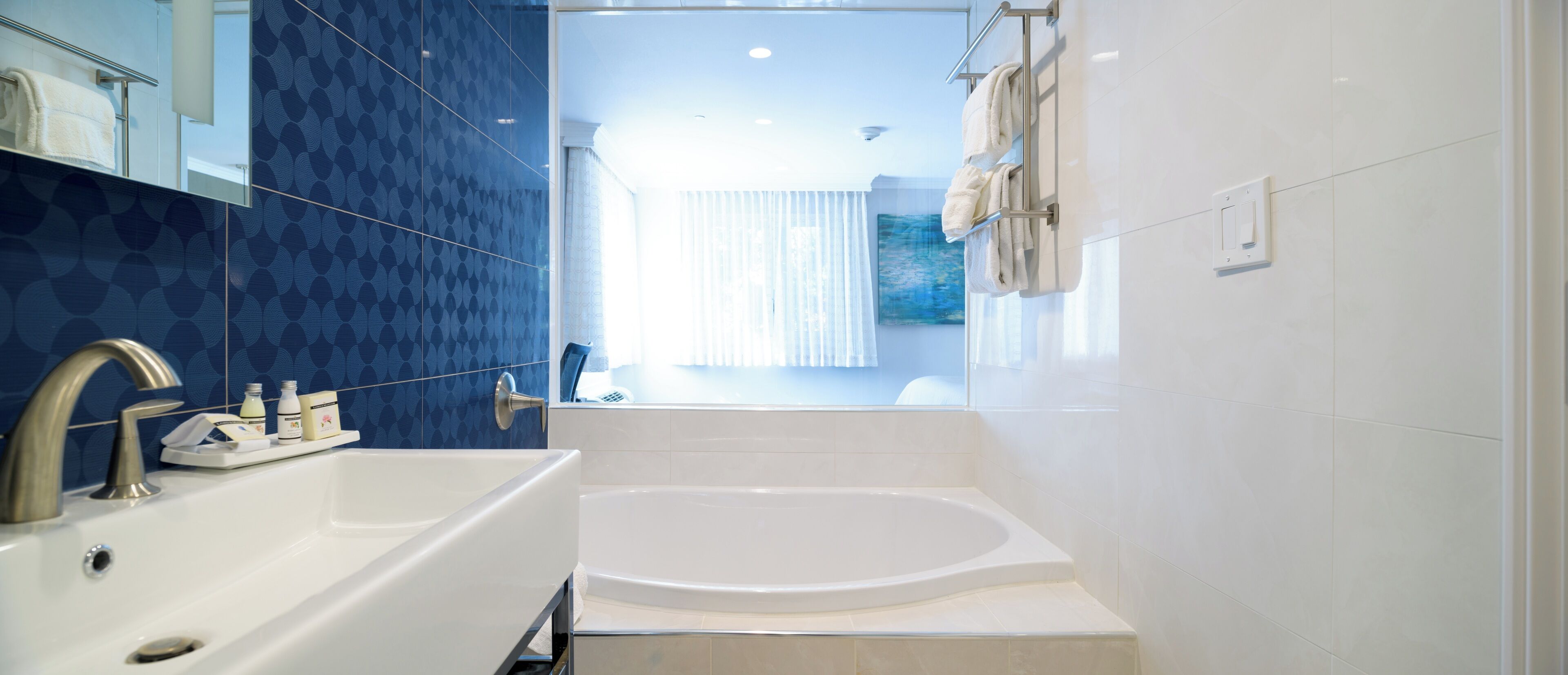 A modern bathroom with a large bathtub, a sink with a faucet, and a mirror above the sink.