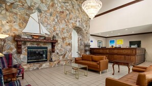 A lobby with a stone wall, fireplace, leather sofas, a glass coffee table, and a reception desk. - Days Inn by Wyndham Lexington (Lexington)