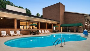 A swimming pool with lounge chairs and umbrellas, a covered seating area, and a brick building. - Days Inn by Wyndham Lexington (Lexington)