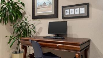 Een houten bureau met een computer, een stoel en een potplant.