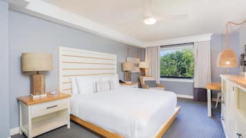 A modern hotel room with a large bed, bedside tables, a desk, and a view of the outdoors.