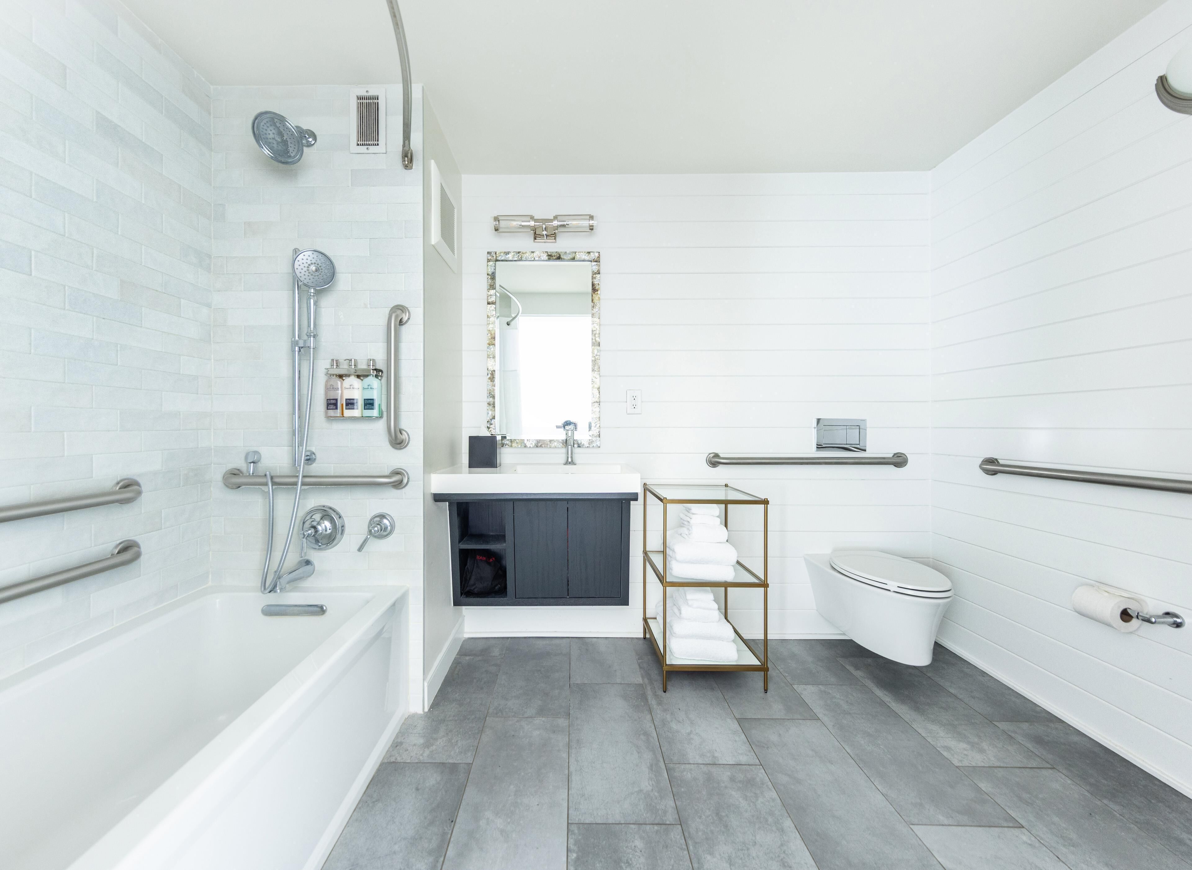 Une salle de bain moderne équipée d’une baignoire, d’une douche, de toilettes et d’un meuble-lavabo avec un miroir.
