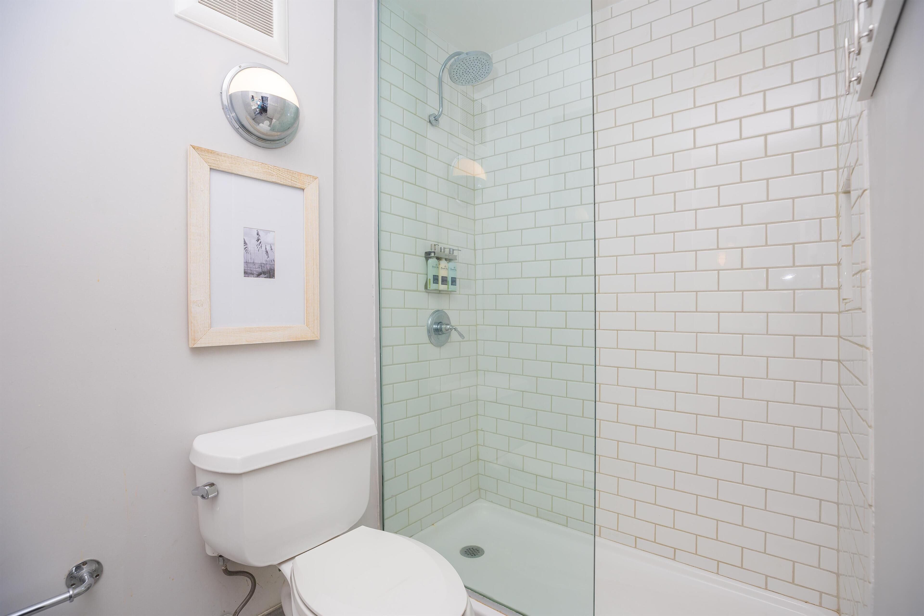 Een badkamer met een toilet, een fotokader aan de muur en een douchecabine met glazen wanden.