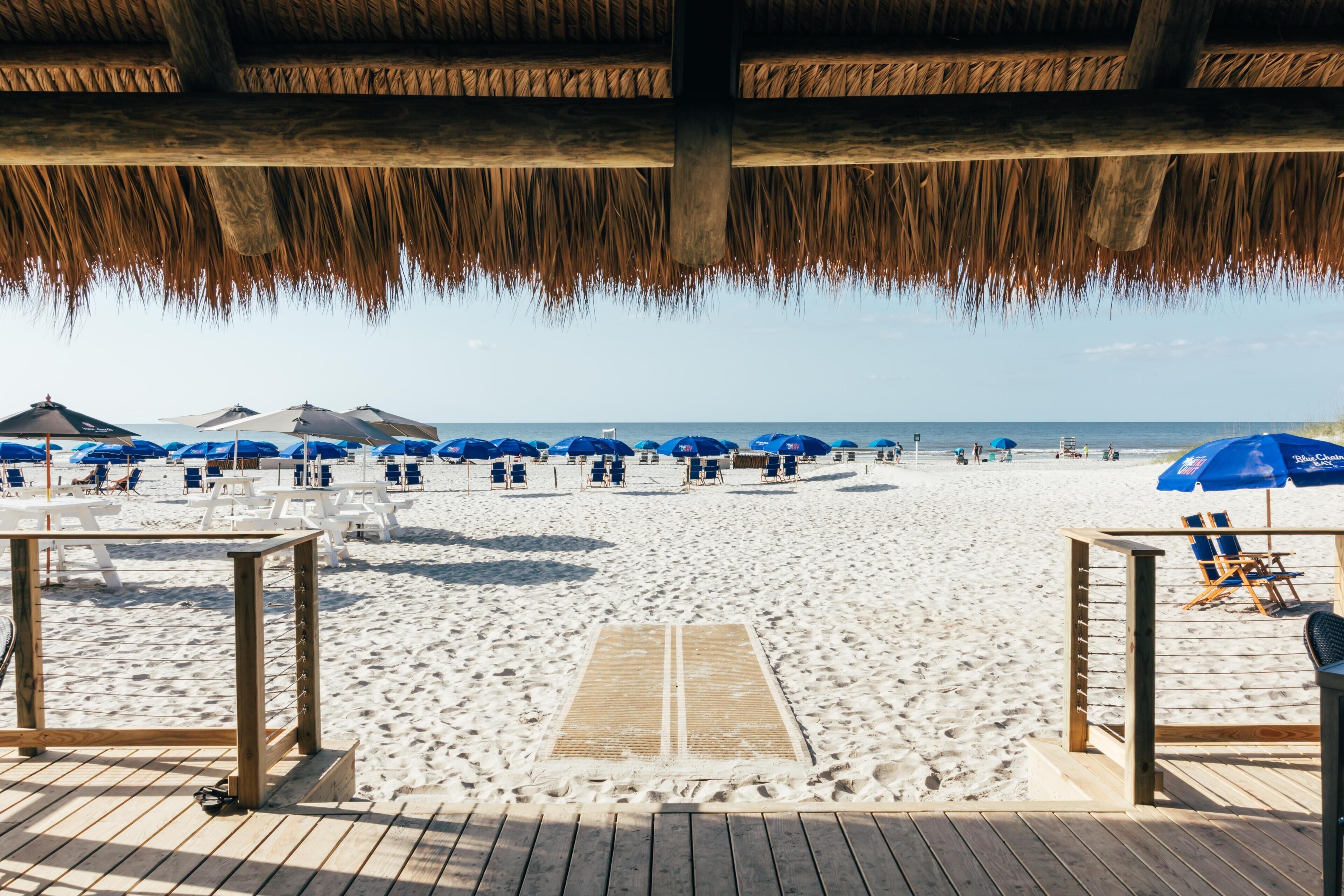 A beach with wooden deck, umbrellas, and beach chairs.