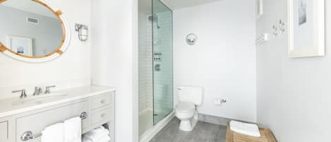 A modern bathroom with a vanity, toilet, shower, and a wooden bench.