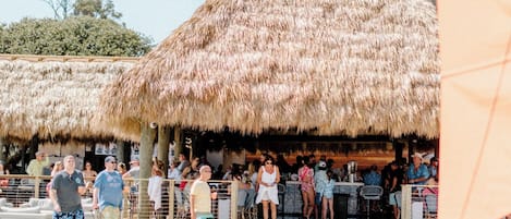 Un bar junto a la playa con techos de paja y suelo de arena.