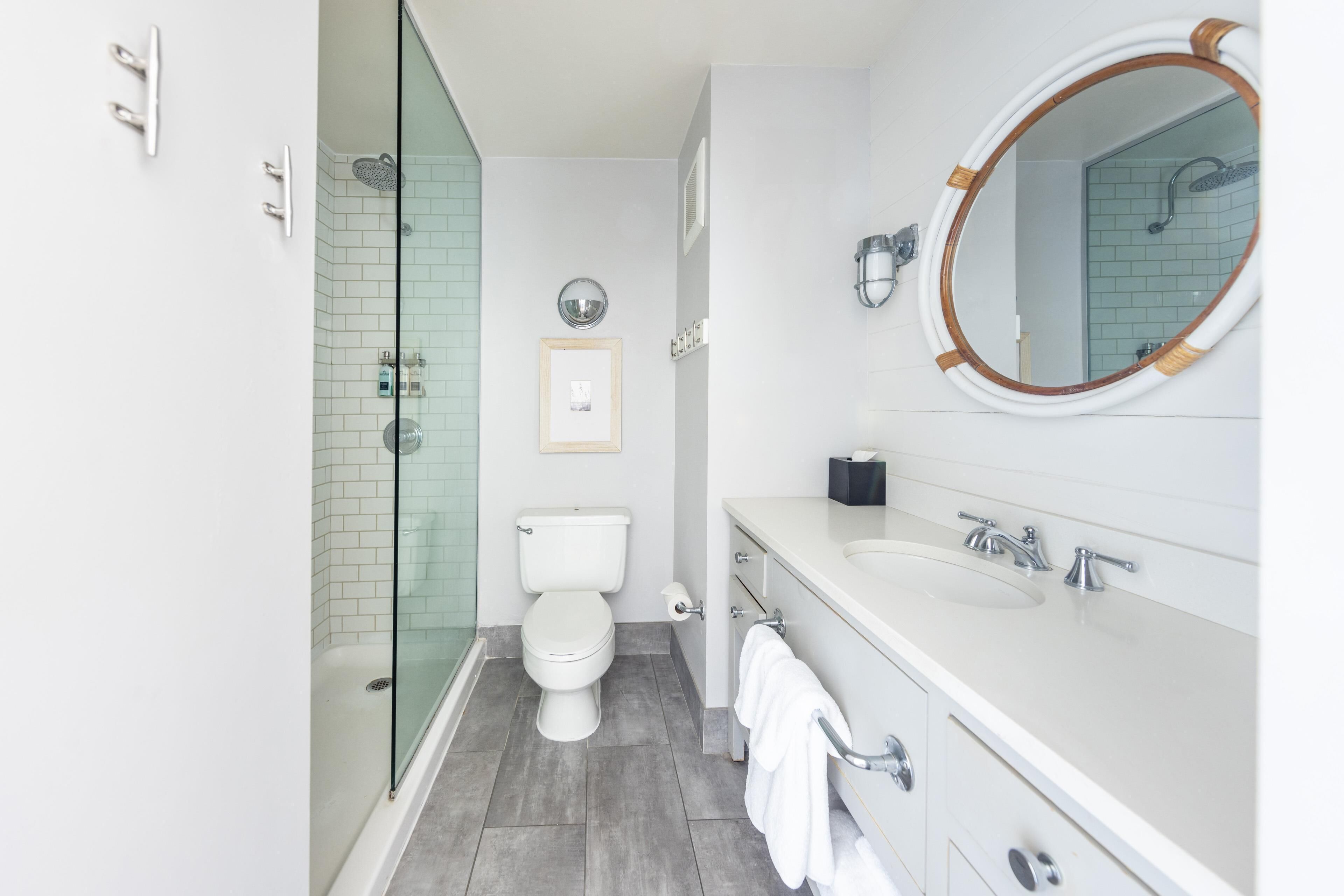 Un baño moderno con cabina de ducha de vidrio, inodoro, lavabo con espejo y barra para toallas.