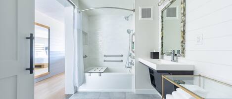 Une salle de bain moderne équipée d’une douche, d’une baignoire, d’un meuble-lavabo avec un miroir et d’un lavabo à vasque en verre.
