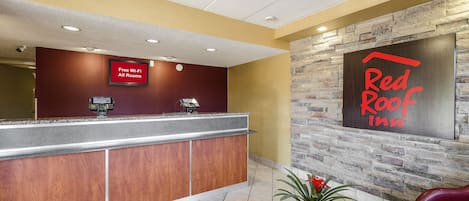 Ein Empfangsbereich mit einer Rezeption, einem Schild, das kostenloses WLAN anzeigt, und dem Schild eines Red Roof Inn.