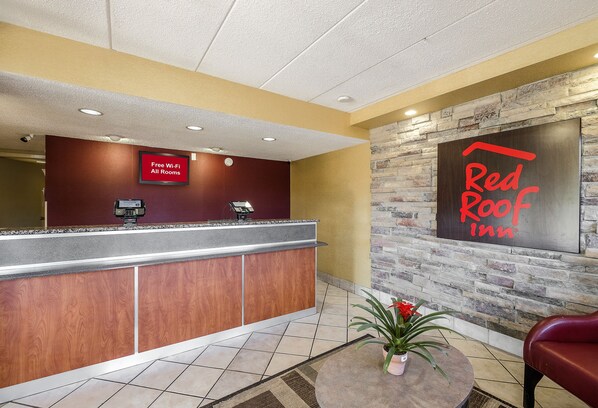 A reception area with a counter, a sign indicating free Wi-Fi, and a Red Roof Inn sign. - Red Roof Inn Columbus East - Reynoldsburg (Columbus)