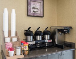 A coffee station with a Bunn coffee machine, disposable cups, and various coffee pods.