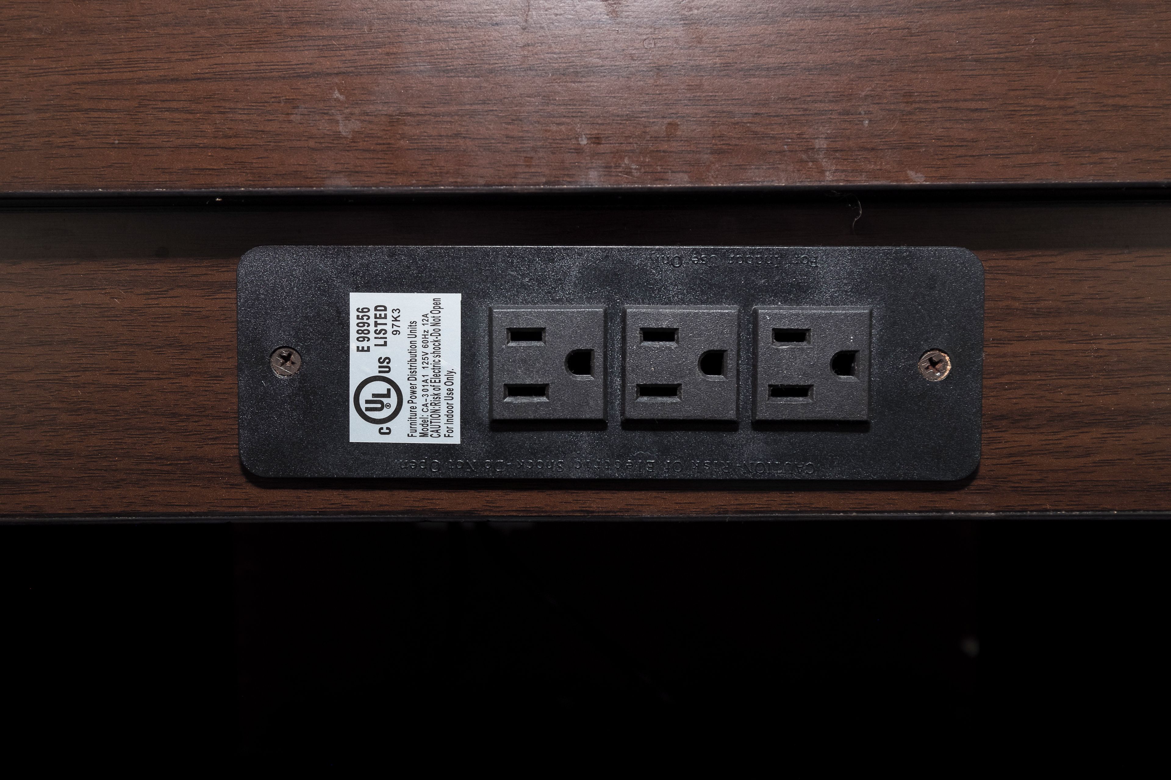 A black electrical outlet with three sockets and a label indicating it is a UL listed product.
