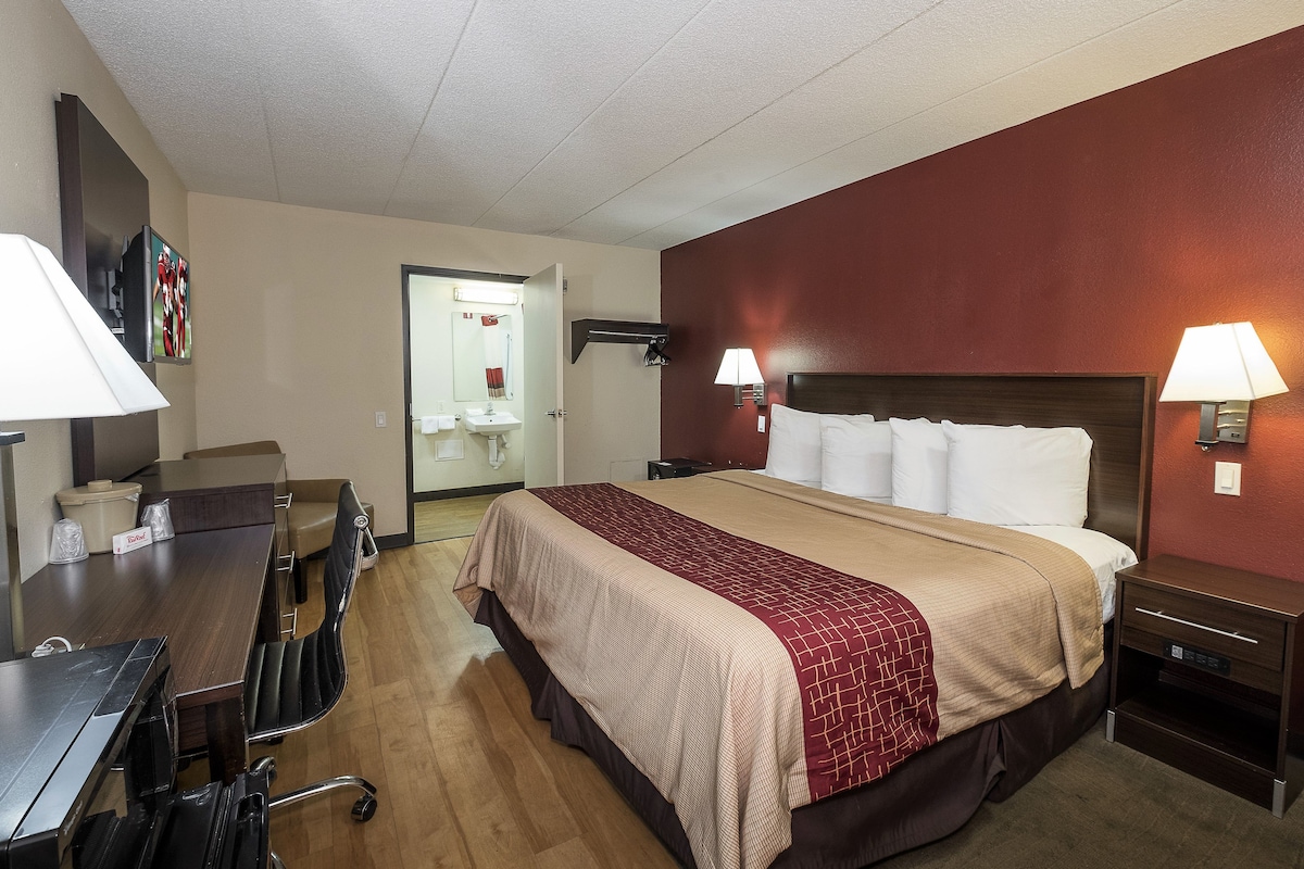 A hotel room with a bed, bedside tables, a desk, and a chair.