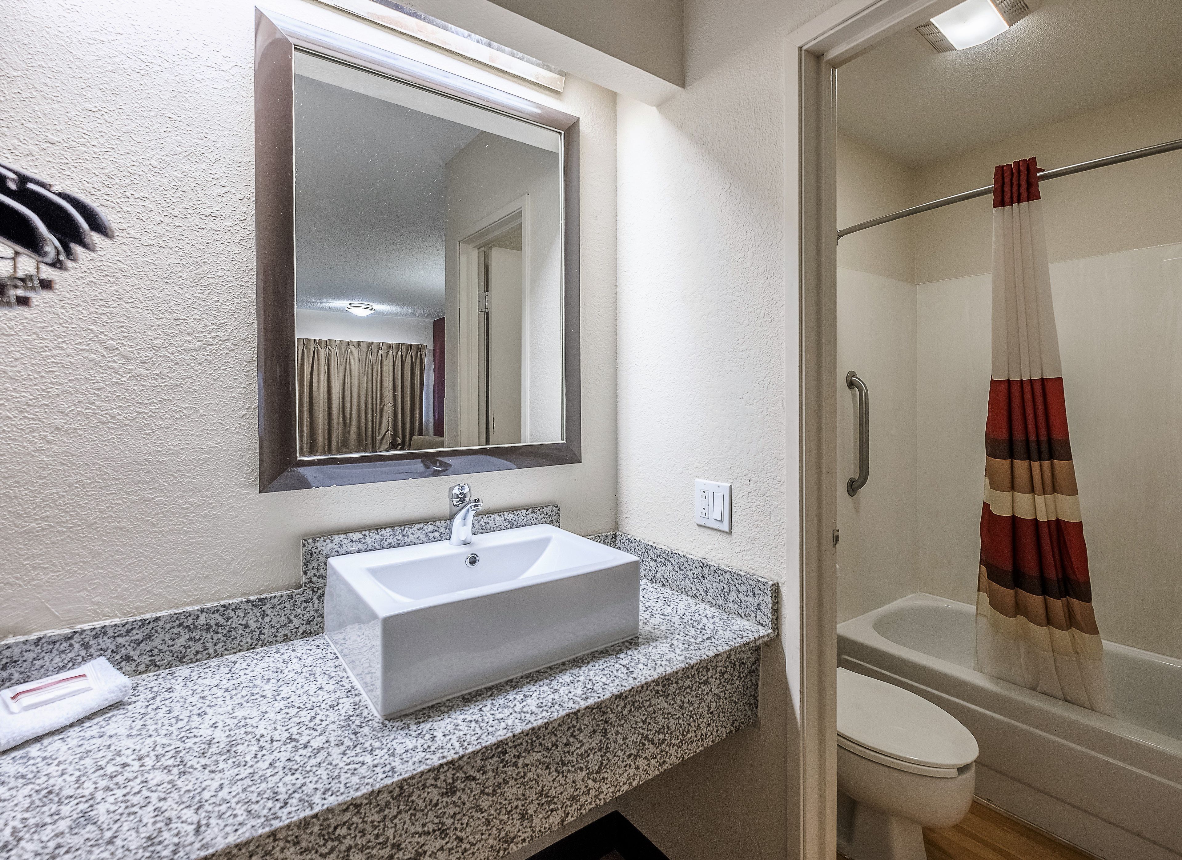 Un baño con lavamanos, espejo, cortina de ducha e inodoro.