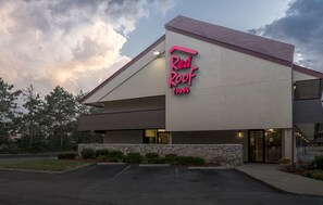 A Red Roof Inn with a stone facade, a sloped roof, and a parking lot.
